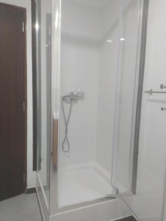 a bathroom with a shower with a glass door at Ginjals-67 Quarto Branco in Almargem do Bispo