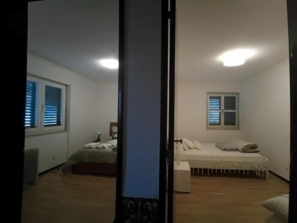 a room with two beds and a mirror at Ginjals-67 Quarto Branco in Almargem do Bispo