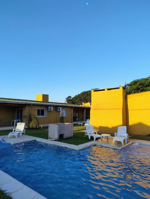 a pool with two chairs and a table in a yard at Cabañas Punta Iglesia 4 in Paso de la Patria