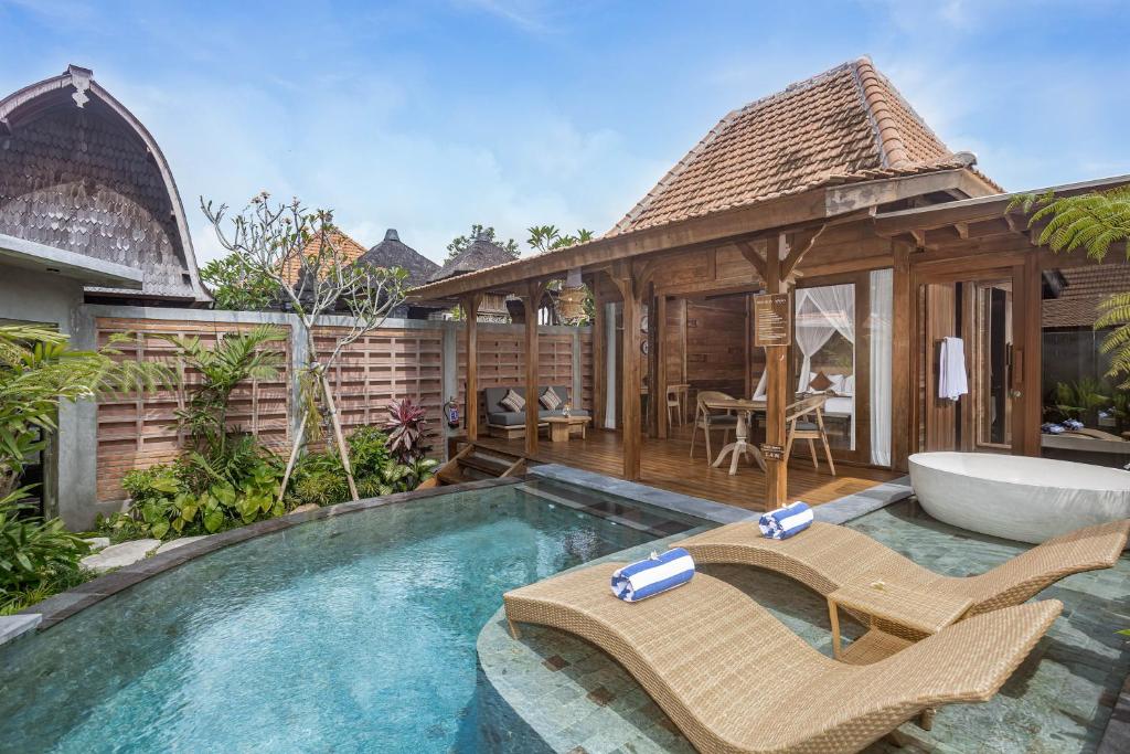 a swimming pool with two chairs and a bath tub at Yana Villas Kemenuh by GenuineHost in Ubud