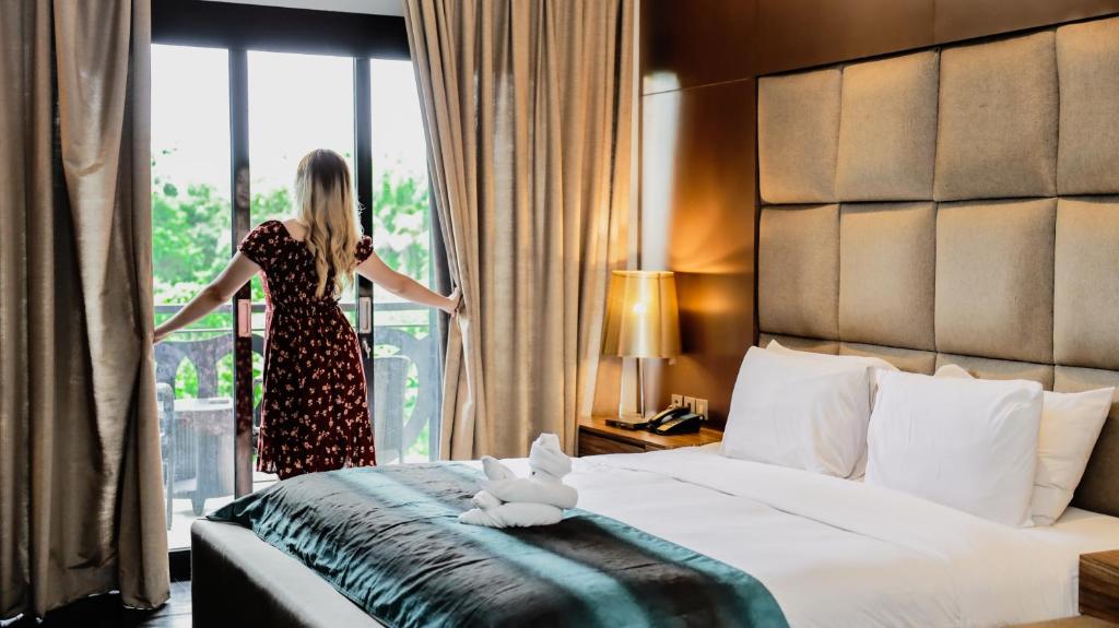 a woman is looking out the window of a hotel room at Amaroossa Suite Bali in Nusa Dua