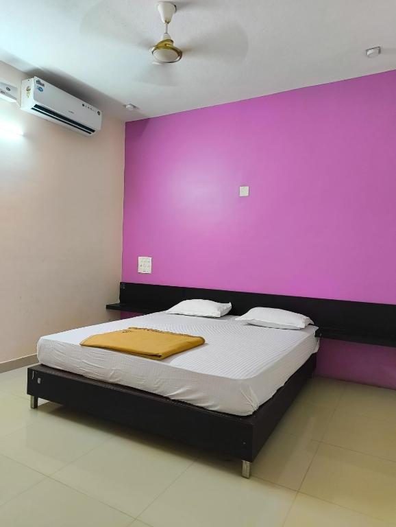 a bedroom with a purple wall and a bed at Kamath regency and cottages in Dharmastala
