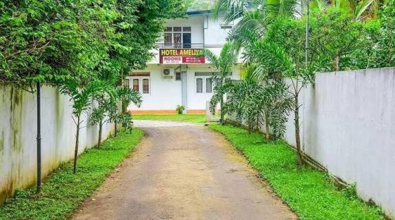 a dirt road in front of a white building at Hotel Ameliya in Kandy