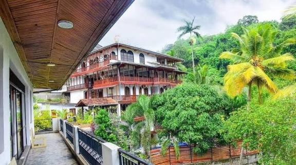 a building with a balcony with trees and bushes at Hotel Ameliya in Kandy