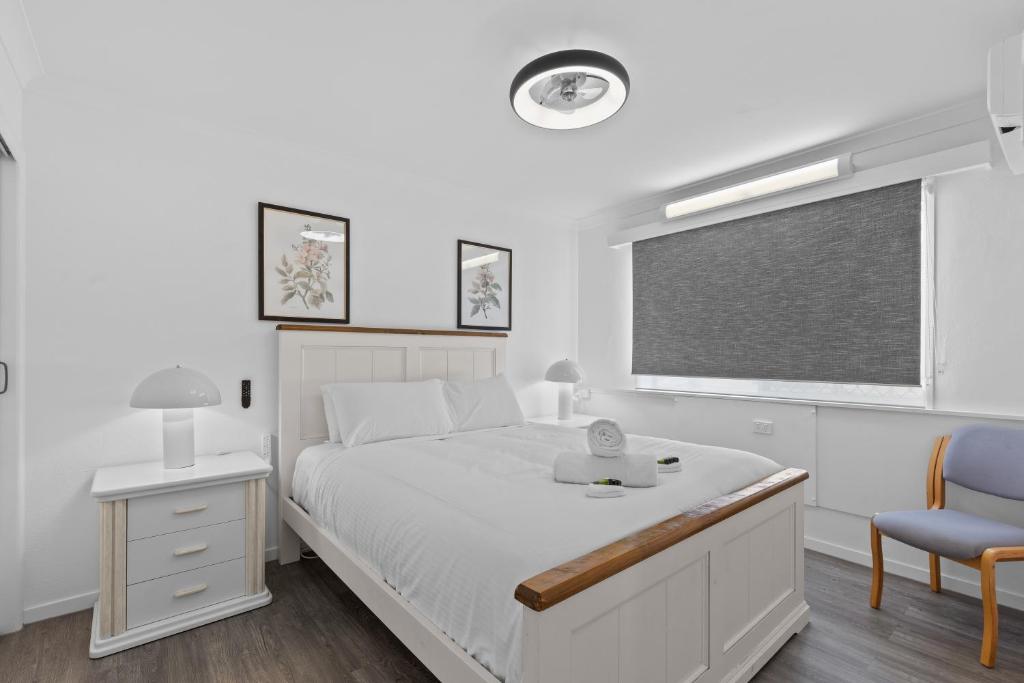 Un dormitorio blanco con una cama y una silla. en Central, Comfortable, Convenient - CCC, en Pialba