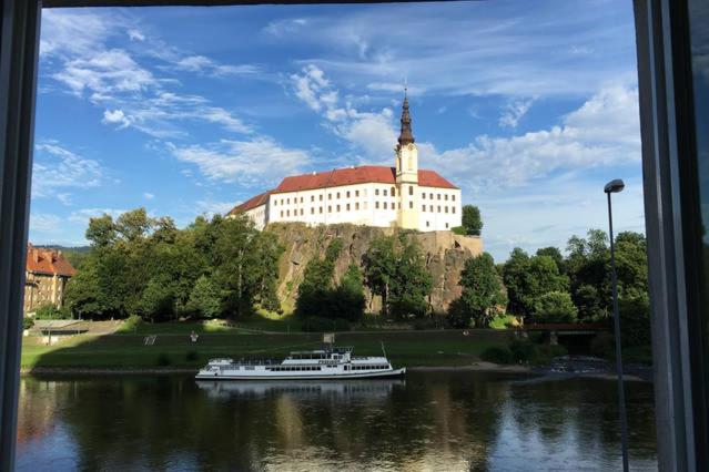 a boat in the water in front of a large building at City Apartment Děčín in Děčín