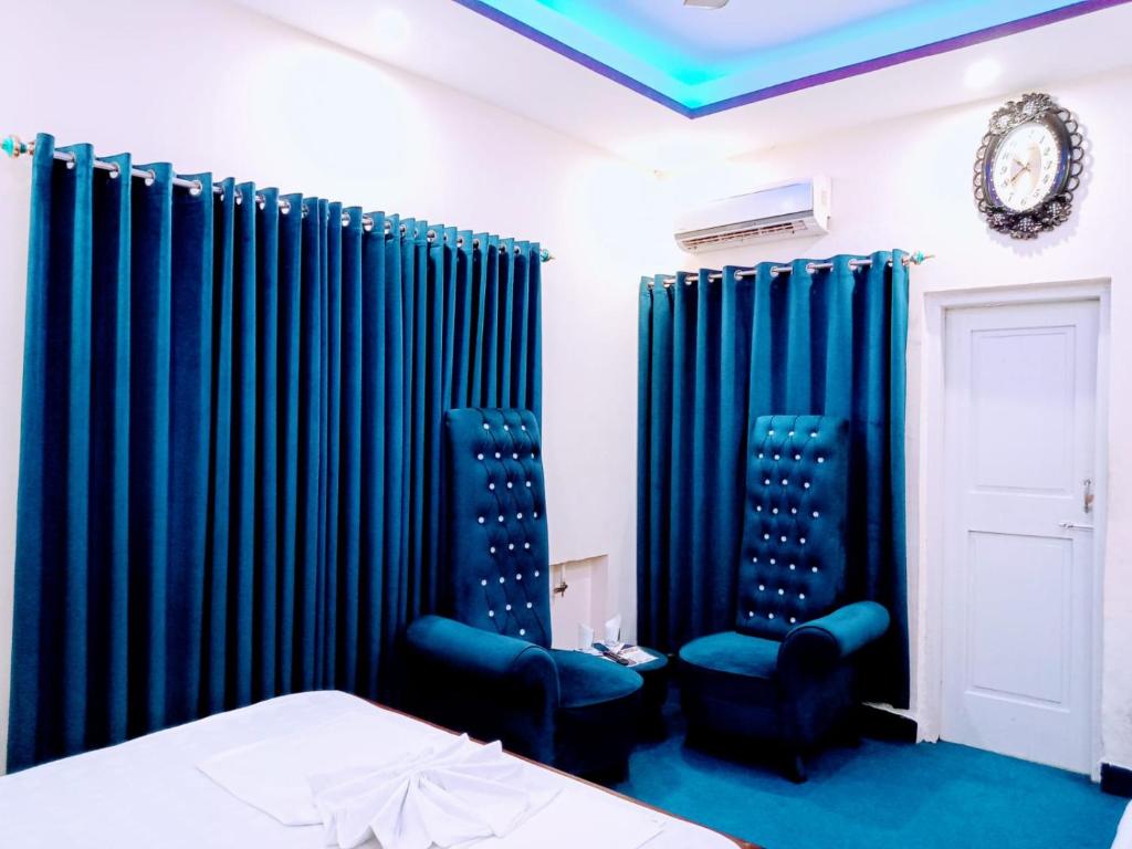 a bedroom with blue curtains and a bed and two chairs at Perfect Lodge Guest House in Islamabad