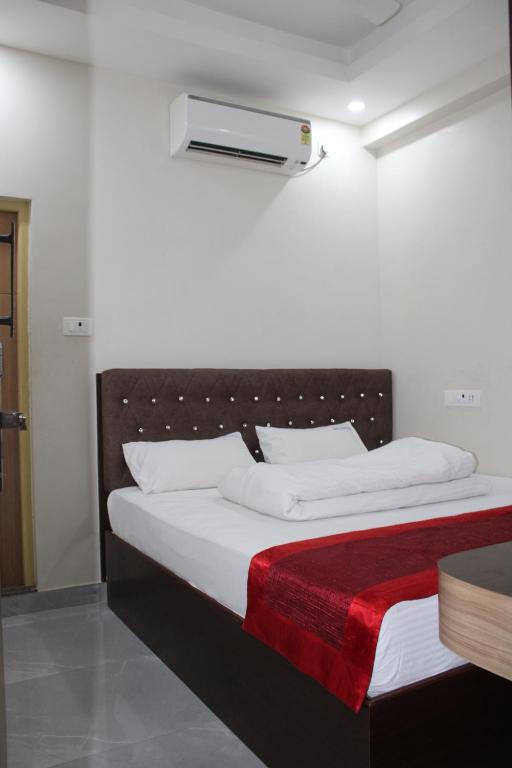ein Bett mit weißer Bettwäsche und einer roten Decke in der Unterkunft SRG Shivam Residency in Tiruvannāmalai