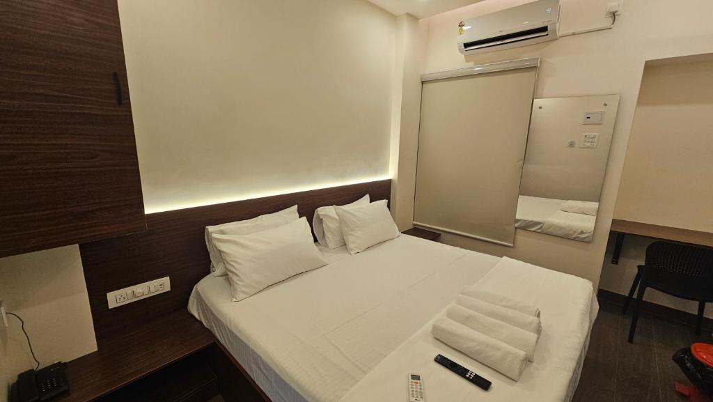 a bedroom with a white bed with a mirror and a desk at Chippy Inn Tharamani in Chennai