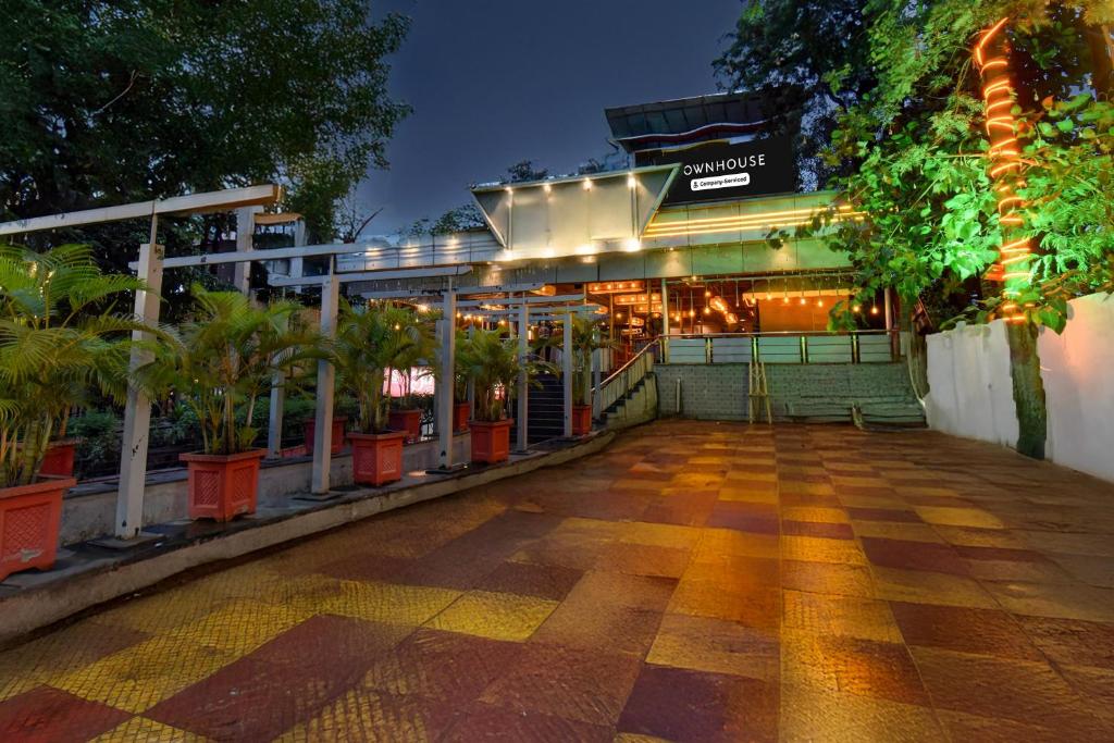 un bâtiment avec une terrasse bordée de palmiers. dans l'établissement Super Townhouse Balewadi Stadium Pune Formerly Hotel Sarovar, à Pune