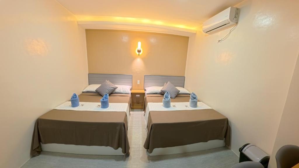 twee bedden in een kamer met een licht aan de muur bij NINIE'S PLACE in Puerto Princesa City