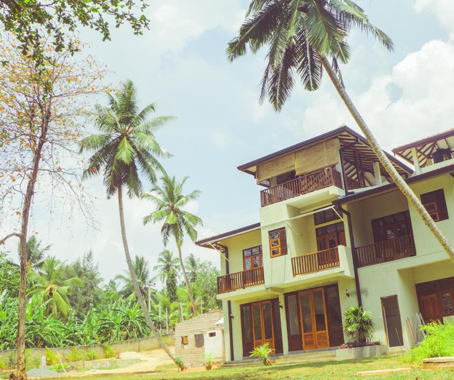 a house with palm trees in front of it at Surf Range in Matara