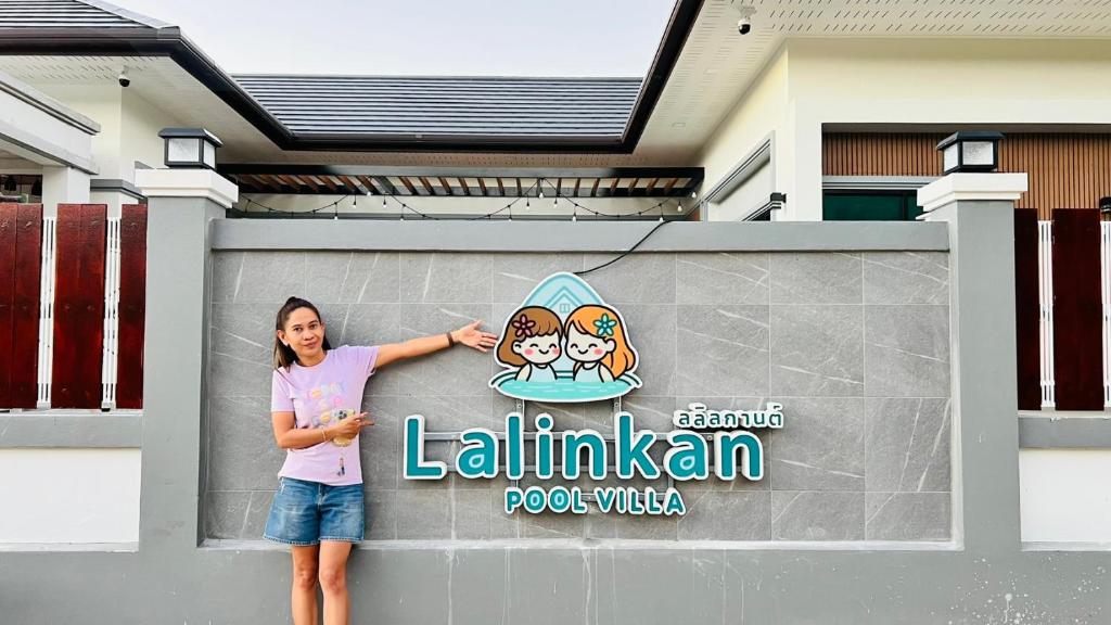 a woman standing next to a sign on a building at lalinkan poolvilla 