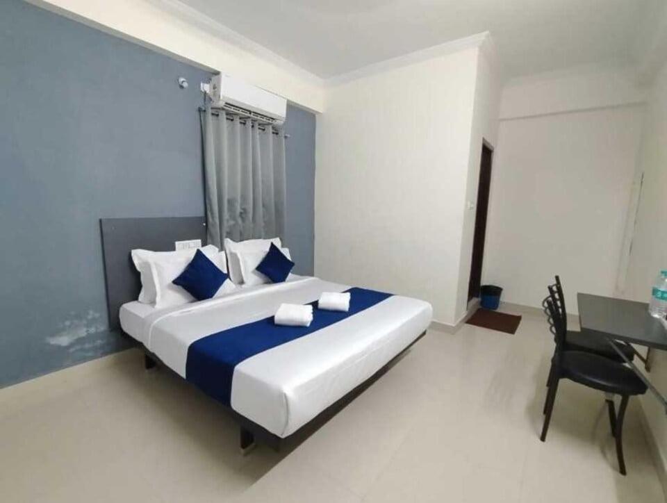 a bedroom with a large bed with blue and white pillows at Hotel O Rajahmundry Central Railway Station Formerly Sanjeevi Residency in Godāvari