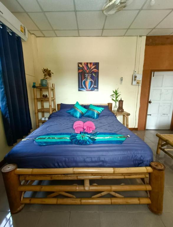 a bed with blue sheets and pink flowers on it at June Guest House 1 in Thong Sala