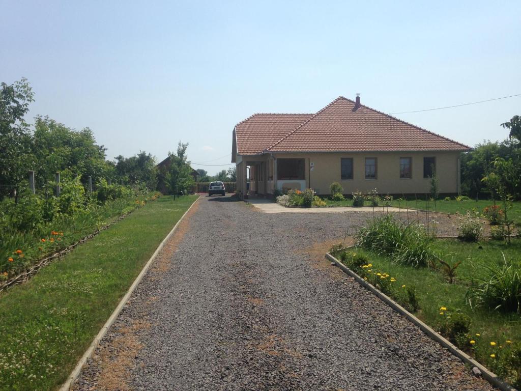 a house on a gravel road next to a yard at Kölcsey Kúria Vendégház in Szatmárcseke