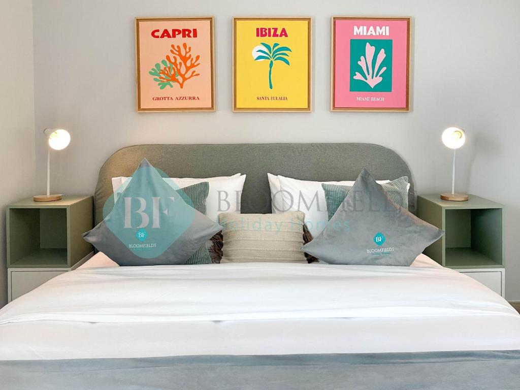 a bedroom with a bed with four pictures on the wall at Bloomfields Relaxing 1Br in Yas Island Waters Ed in Yas Island