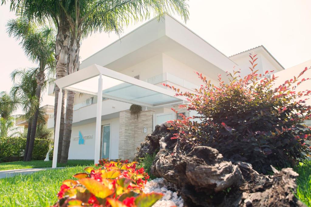 a white house with palm trees and flowers at Hotel America in Scafati