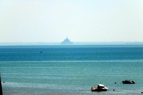 Un gran cuerpo de agua con dos barcos en él. en Un nid douillet sous les toits, en Cancale