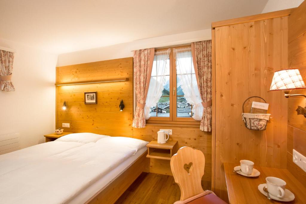 a bedroom with a large bed and a window at Hotel Romantica in Zermatt