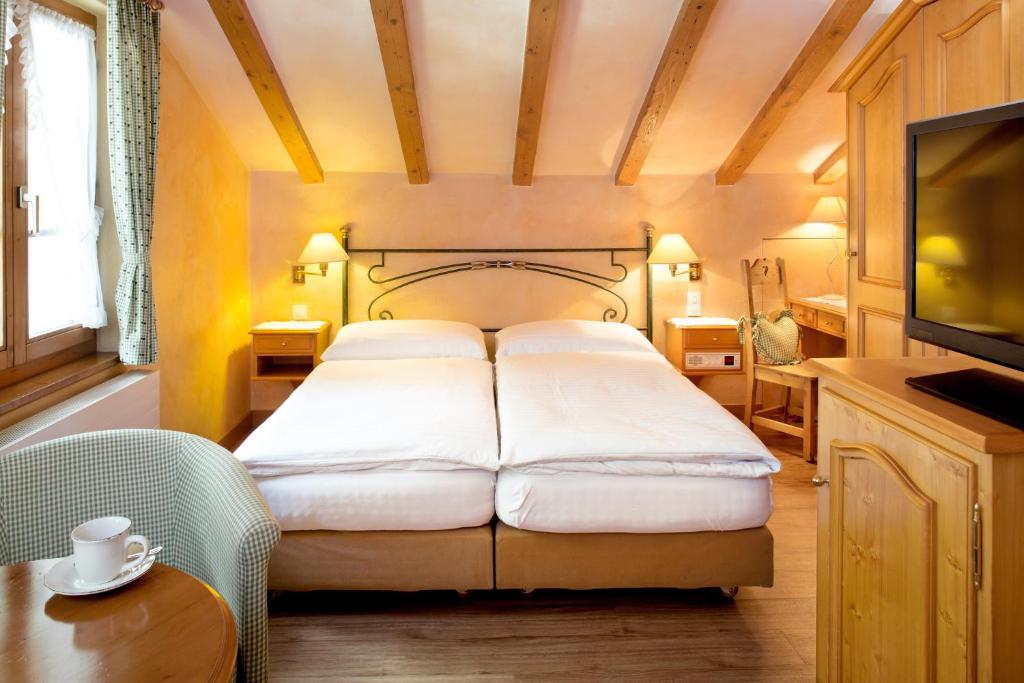 a bedroom with a bed and a tv in a room at Hotel Romantica in Zermatt