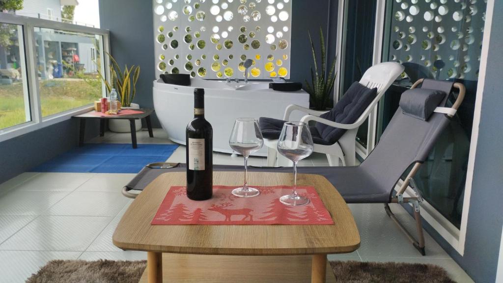 a bottle of wine and two glasses on a table at The Village in Prakhon Chai