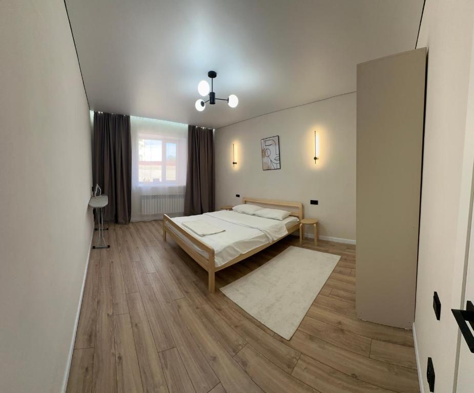 ein Schlafzimmer mit einem Bett und einem Holzboden in der Unterkunft Новая квартира со всеми условиями Сити центре in Oral