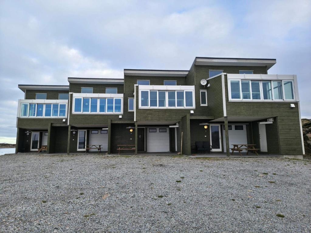 une grande maison aux fenêtres bleues sur une allée de gravier dans l'établissement 6 person holiday home in Dyrvik, à Dyrvik