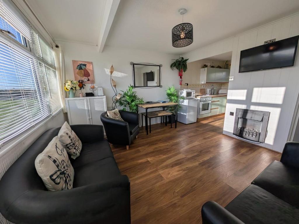 a living room with a couch and a table at The Green One, Sunbeach, Scratby - Two bed chalet, sleeps 5, free Wi-Fi, pet friendly, bed linen and towels included plus free entry to onsite clubhouse in Scratby