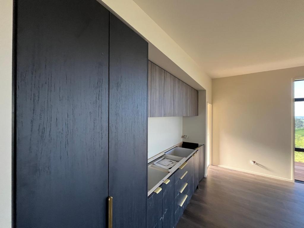 a kitchen with dark wood cabinets and a sink at Golden Ridge Retreat in Otorohanga