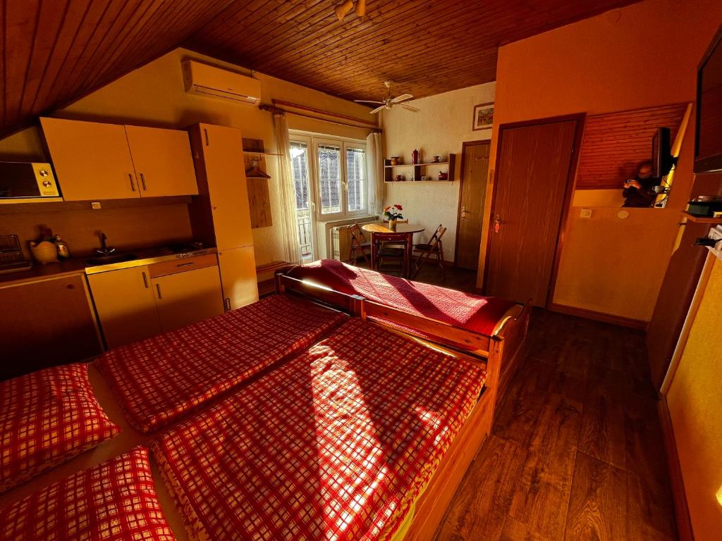 a bedroom with a bed and a kitchen with a table at Mekina Guesthouse in Maribor