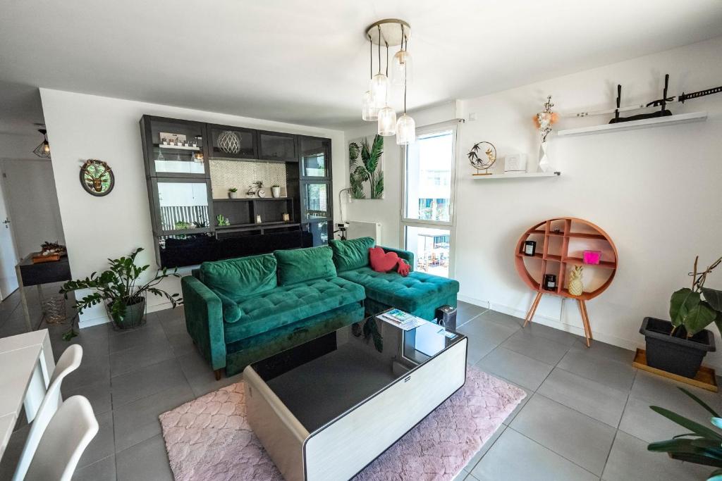 a living room with a green couch and some plants at Bright Apartment Near the lake in Bordeaux