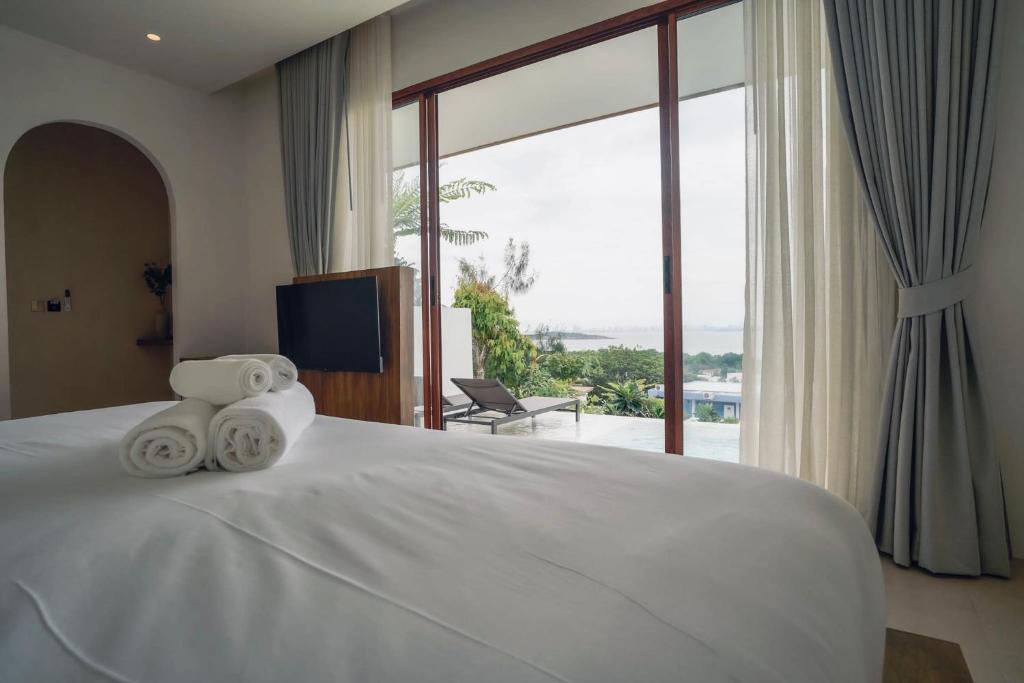 a bedroom with a large white bed with a large window at Pichcha Kohlarn in Ko Larn