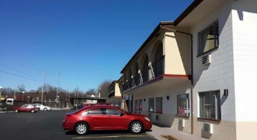 a red car parked in a parking lot next to a building at America's Best Inn Urbana Champaign in Champaign