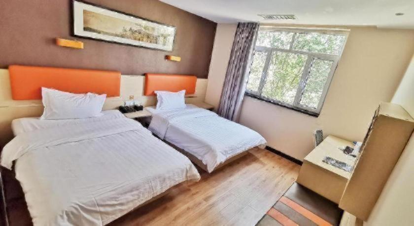 une chambre avec deux lits et une fenêtre dans l'établissement 7 Days Premium· Tianjin Binhai International Airport, à Tianjin