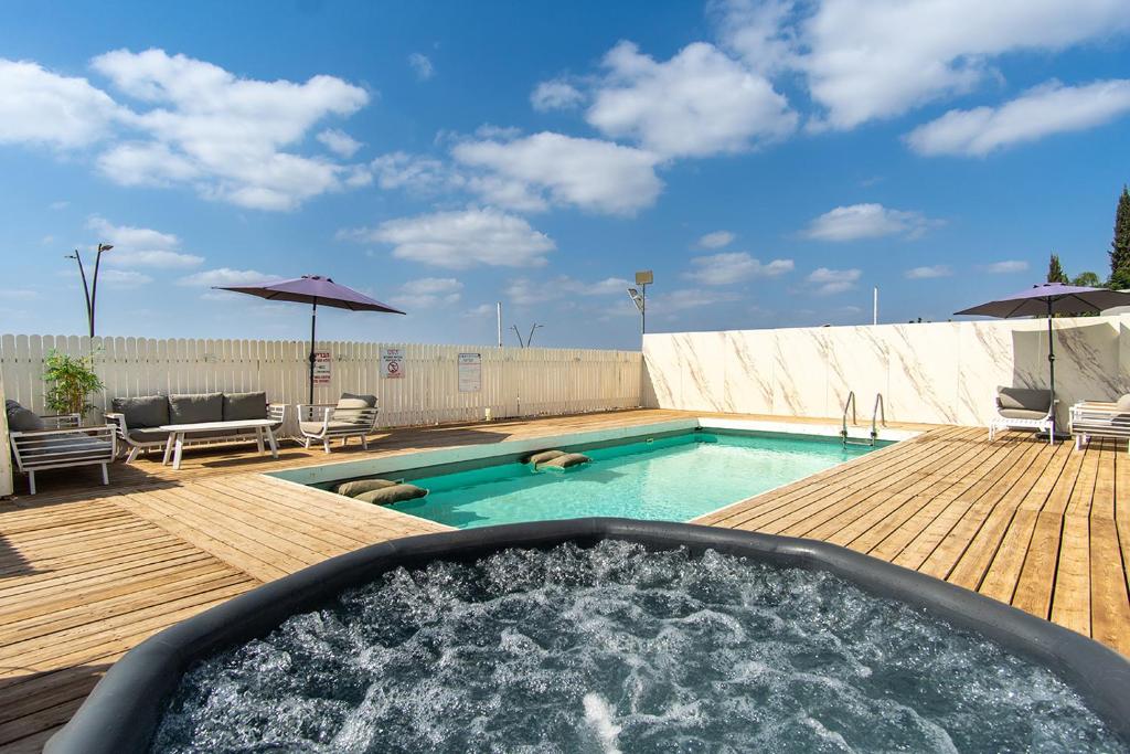 a pool with a hot tub on a wooden deck at וילת האגם - וילה מהממת בטבריה עם בריכה פרטית in Tiberias