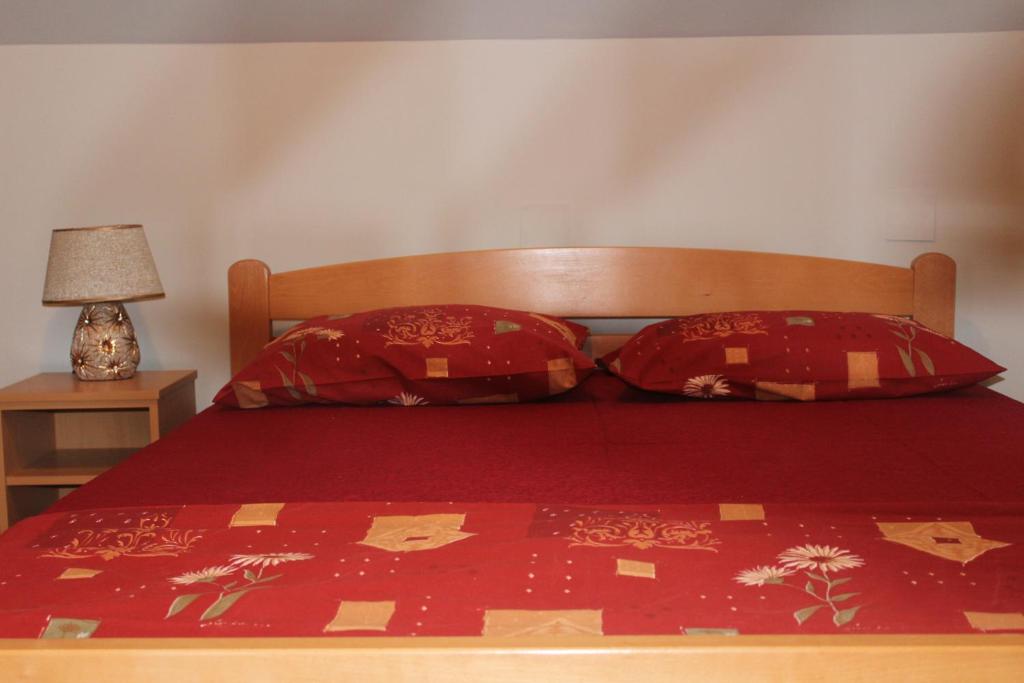 1 dormitorio con 1 cama con sábanas y almohadas rojas en Sofija apartmani en Arandjelovac