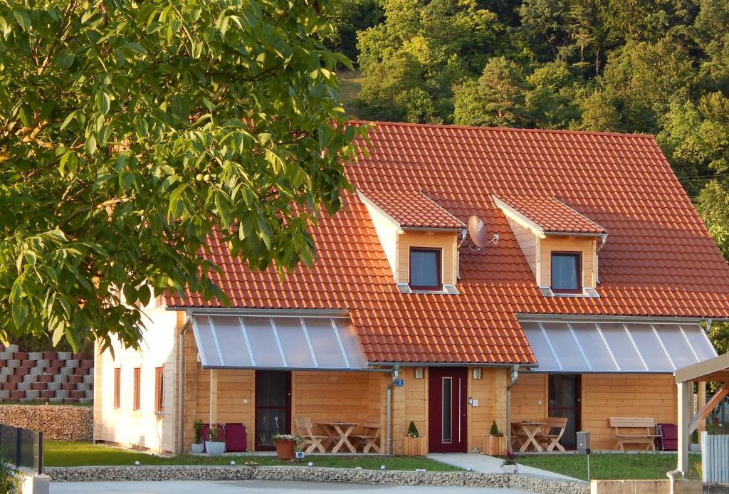 ein Haus mit rotem Dach und Sonnenkollektoren darauf in der Unterkunft Holzblockhaus Stark in Kelheim