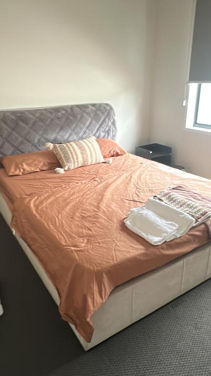 a bed with an orange comforter and pillows on it at Comfortable Home stay in Pimpama