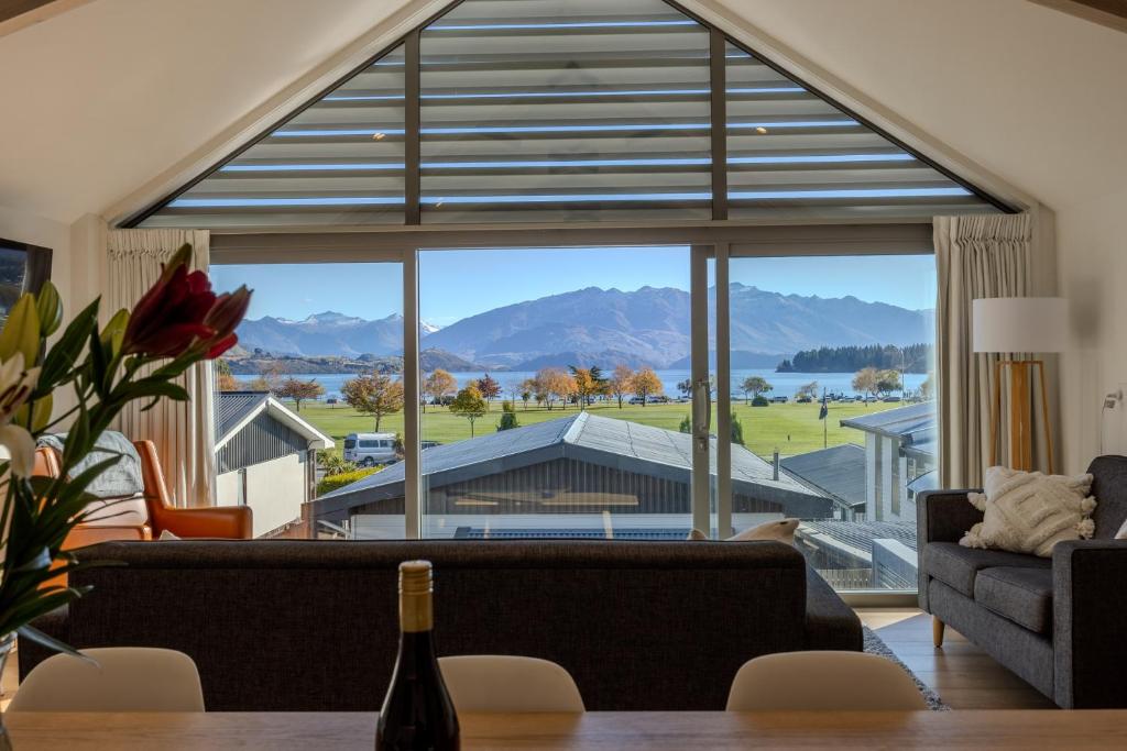 - un salon avec une grande fenêtre donnant sur les montagnes dans l'établissement Aspiring View Apartments, à Wanaka