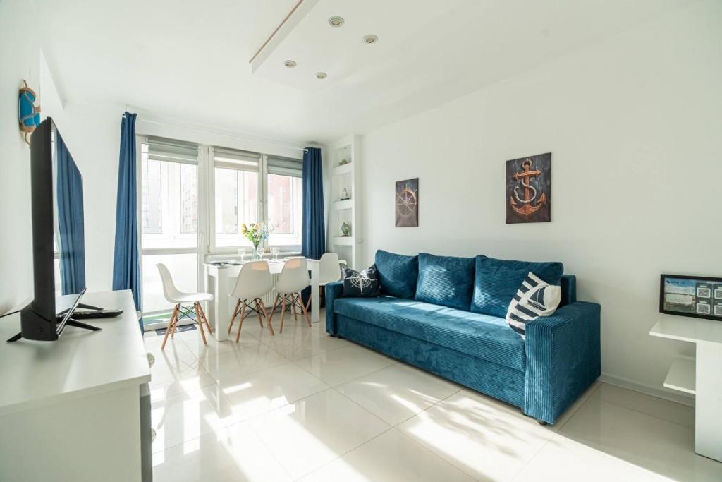 a living room with a blue couch and a table at Apartly - Apartament Wyszyńskiego z loggią in Szczecin