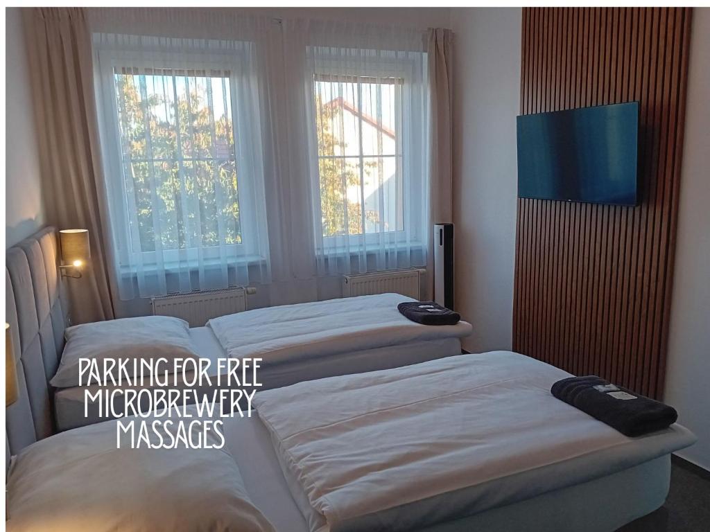 two beds in a room with two windows at Hotel u Budvaru in České Budějovice