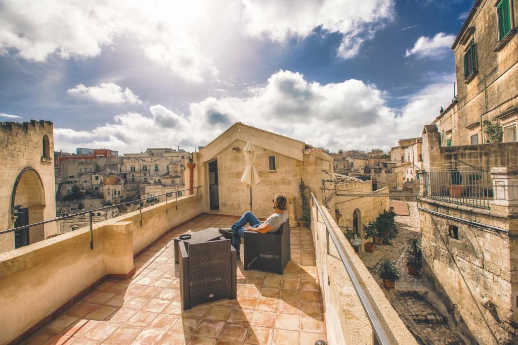 una mujer sentada en un balcón con vistas a una ciudad en La Casa di Ele, en Matera