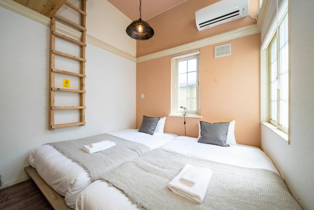 dwa łóżka w pokoju z dwoma oknami w obiekcie Guest House NANMO w mieście Minami-jūichijō