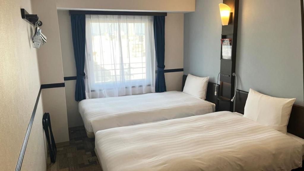 twee bedden in een kleine kamer met een raam bij Toyoko Inn Osaka Honmachi No2 in Osaka