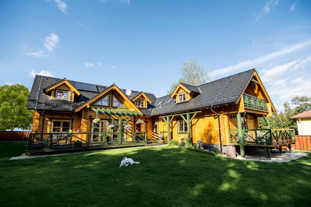 una cabaña de madera con un perro tirado en la hierba en Villa Buky & Chalets en Tatranská Lomnica