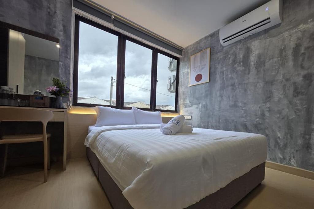 Un dormitorio con una cama con un escritorio y una ventana. en The Cozy Hotel, en Sungai Petani