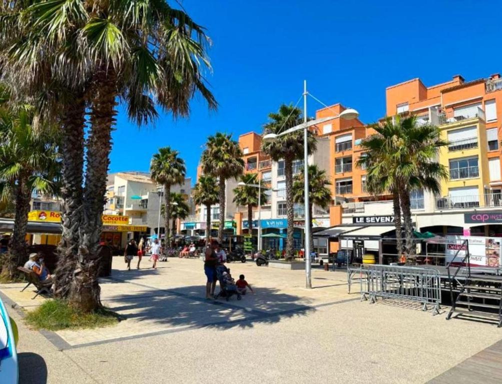 eine Stadtstraße mit Palmen und Gebäuden in der Unterkunft A 100m de la plage A3, Rez-de-chaussee in Cap d'Agde