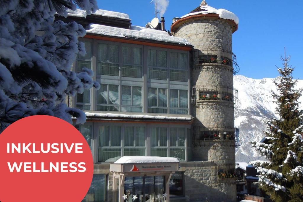 a building with a chimney with the text inclusive wellness at Lifestyle & Spa Hotel Grächerhof in Grächen