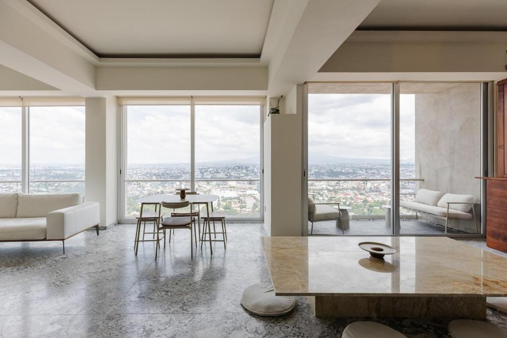 a living room with a table and chairs and windows at Luxury Penthouse with Jacuzzi & Views in Puebla